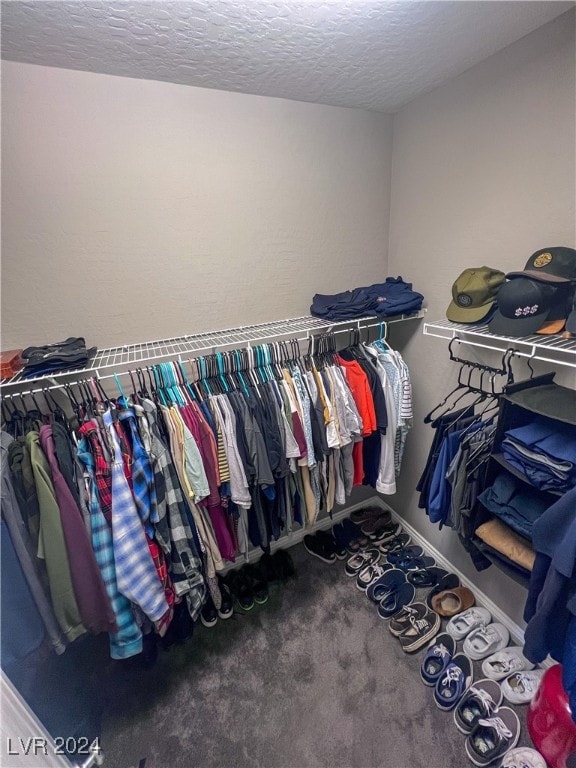 walk in closet with dark colored carpet