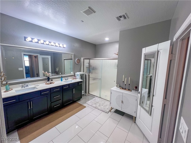 bathroom featuring vanity, a textured ceiling, a shower with shower door, and tile patterned flooring