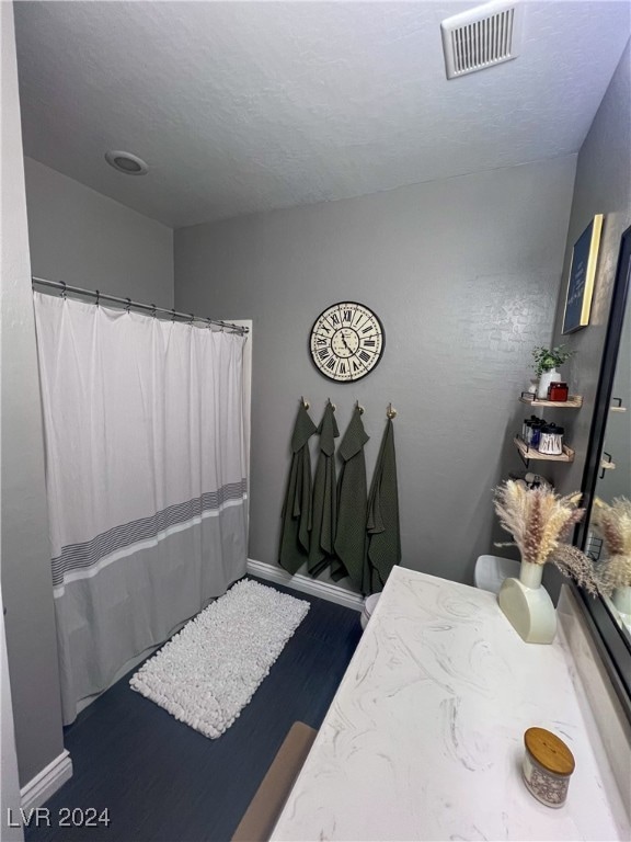 bathroom with curtained shower, hardwood / wood-style flooring, a textured ceiling, and vanity