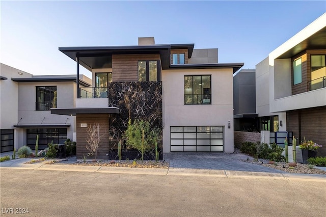 contemporary home featuring decorative driveway, an attached garage, and stucco siding