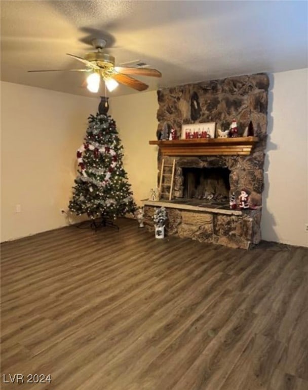 living room with wood-type flooring, ceiling fan, and a stone fireplace