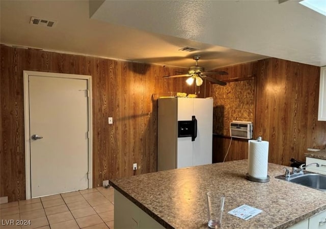 kitchen featuring light tile patterned floors, sink, wood walls, ceiling fan, and white fridge with ice dispenser