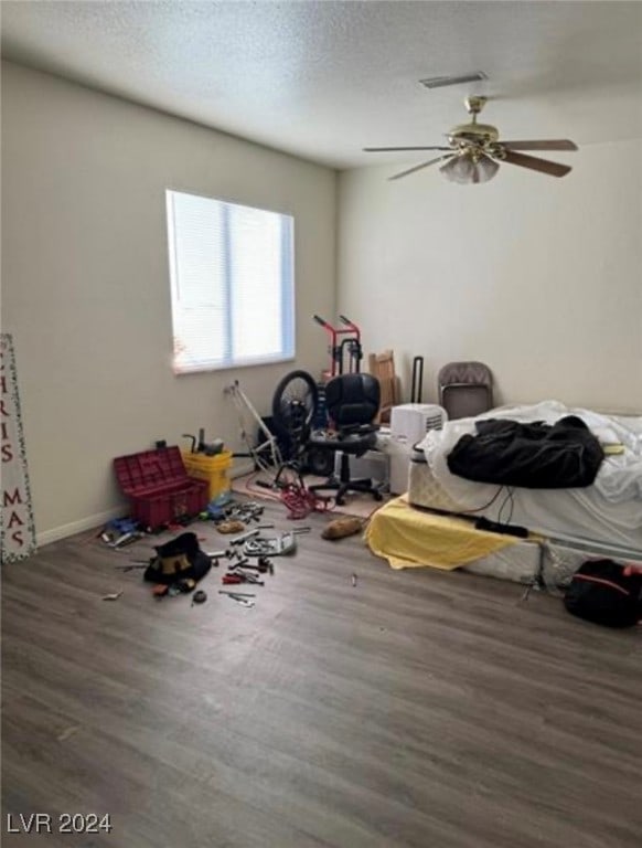 miscellaneous room featuring ceiling fan, dark hardwood / wood-style floors, and a textured ceiling