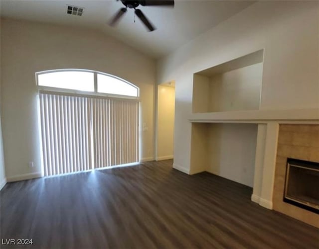 unfurnished living room featuring a tiled fireplace, vaulted ceiling, ceiling fan, and dark hardwood / wood-style floors