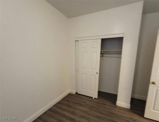 unfurnished bedroom with dark hardwood / wood-style flooring and a closet