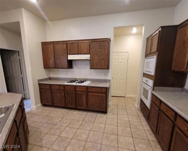 kitchen with white appliances, dark brown cabinets, and light tile patterned floors