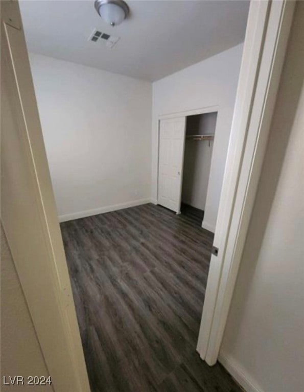 unfurnished bedroom featuring dark wood-type flooring and a closet