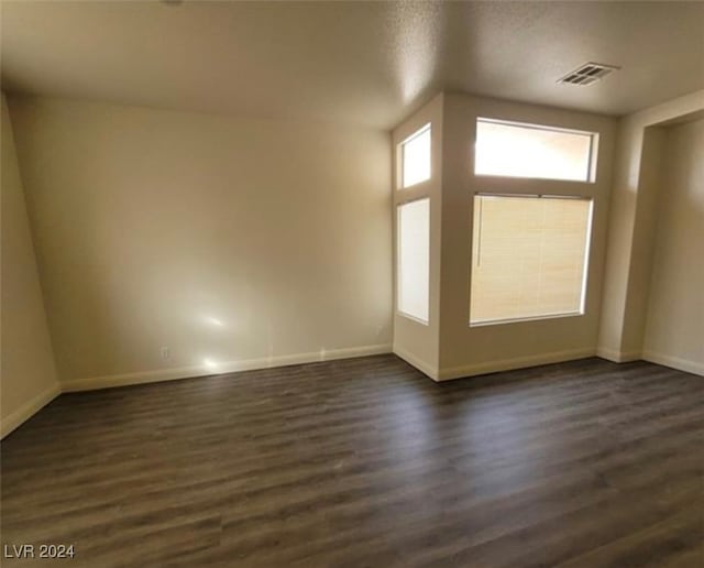 spare room featuring a textured ceiling and dark hardwood / wood-style floors