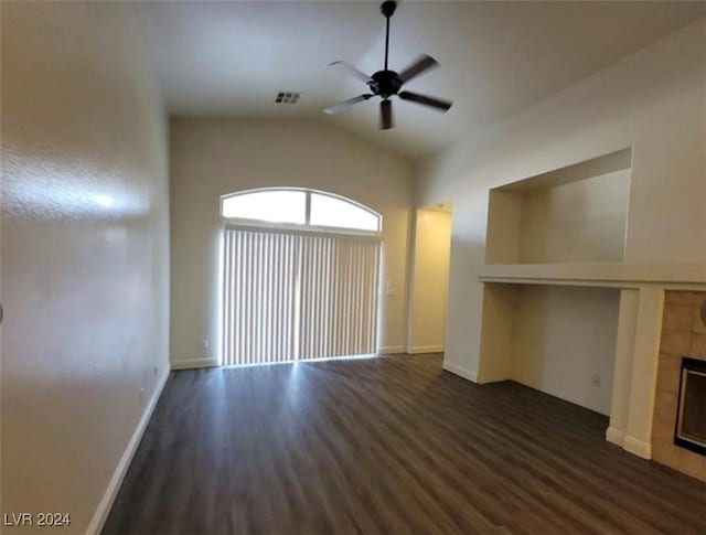 unfurnished living room with dark wood-type flooring, ceiling fan, lofted ceiling, and a tiled fireplace