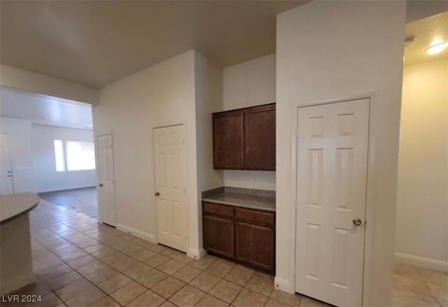 kitchen featuring light tile patterned floors and dark brown cabinetry