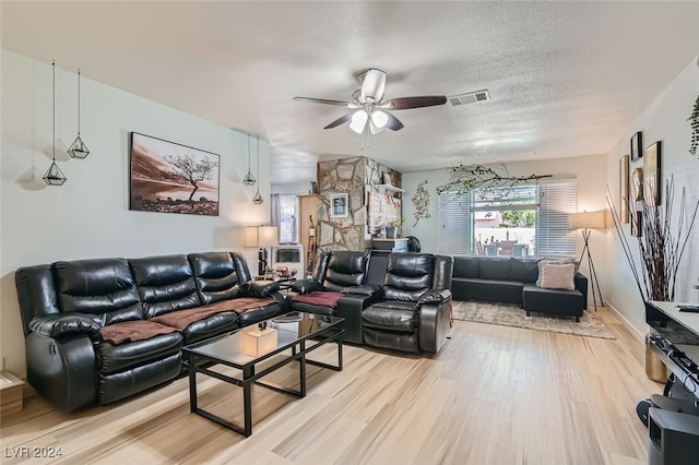 living room with ceiling fan, light hardwood / wood-style floors, and a textured ceiling