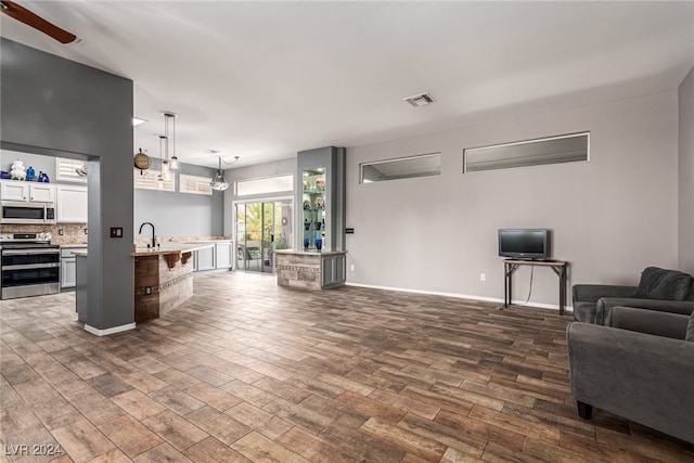 living room featuring dark hardwood / wood-style floors, ceiling fan, and sink