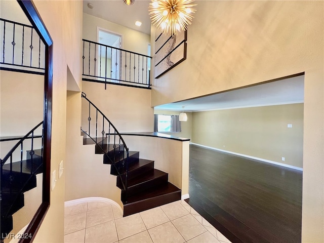 stairs featuring a high ceiling, wood-type flooring, and a chandelier