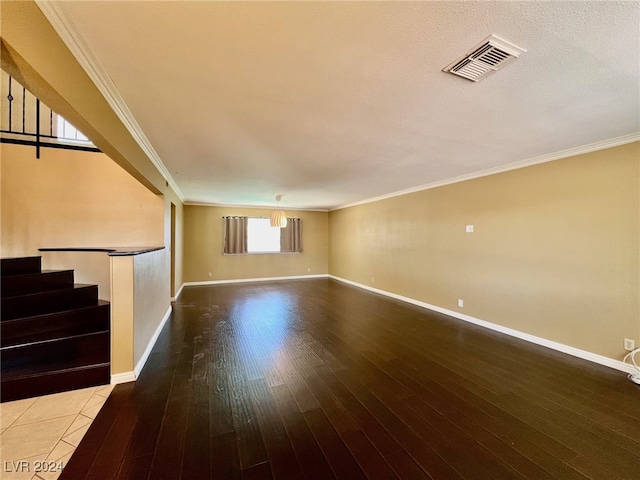 empty room featuring wood-type flooring, crown molding, and a textured ceiling