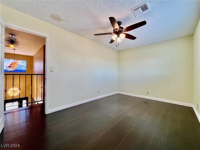 spare room with dark wood-type flooring, ceiling fan with notable chandelier, and a textured ceiling