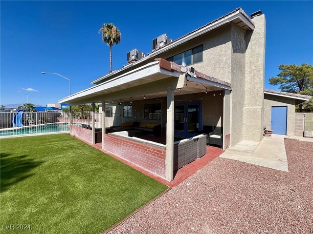 back of house with a fenced in pool, a patio, and a yard