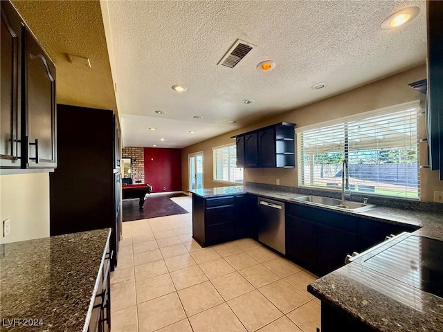 kitchen featuring dishwasher, dark stone countertops, sink, and light tile patterned floors