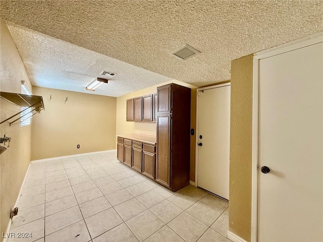 interior space with a textured ceiling and light tile patterned floors