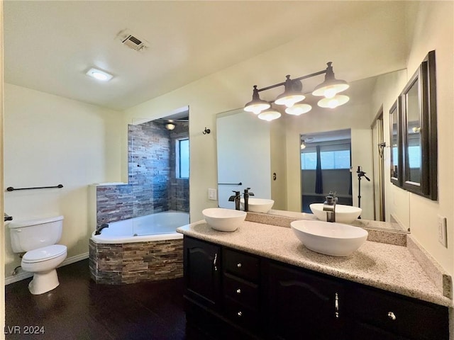 bathroom featuring toilet, vanity, and tiled bath