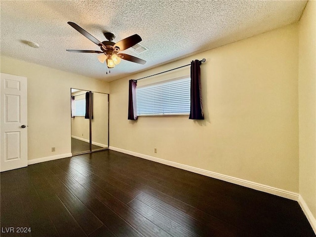 unfurnished bedroom featuring ceiling fan, dark hardwood / wood-style floors, a closet, and a textured ceiling