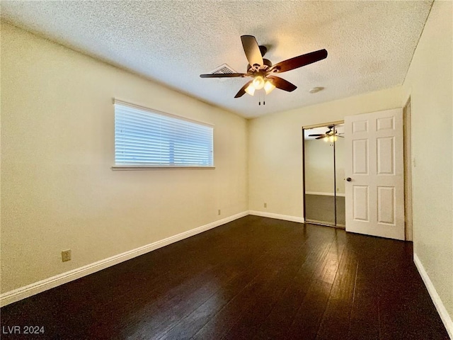 unfurnished room featuring ceiling fan, dark wood-type flooring, and a textured ceiling