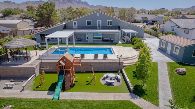 view of swimming pool featuring a mountain view, a playground, and a patio