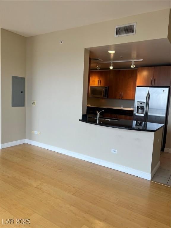 kitchen with appliances with stainless steel finishes, sink, electric panel, and light wood-type flooring