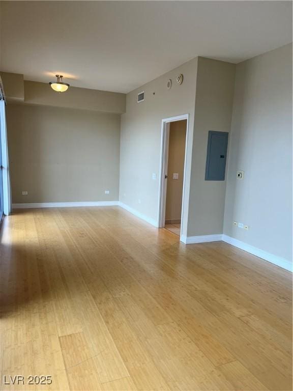 unfurnished room featuring electric panel and light hardwood / wood-style flooring