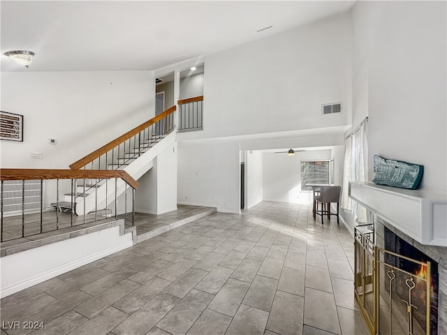 unfurnished living room featuring high vaulted ceiling and ceiling fan