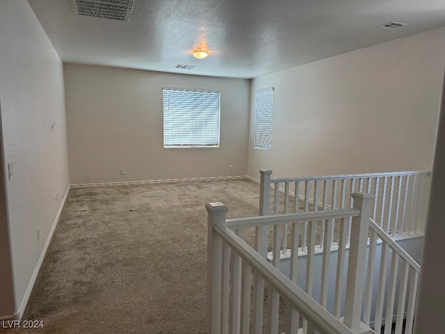 corridor featuring a textured ceiling and carpet flooring