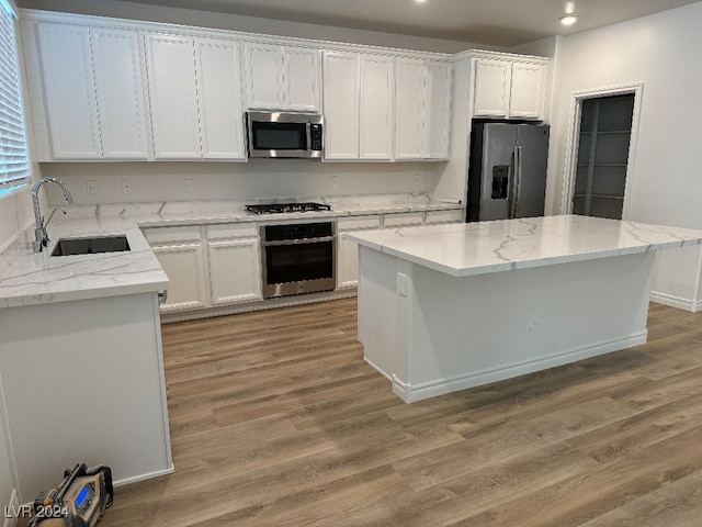 kitchen featuring light hardwood / wood-style flooring, appliances with stainless steel finishes, a center island, sink, and white cabinets