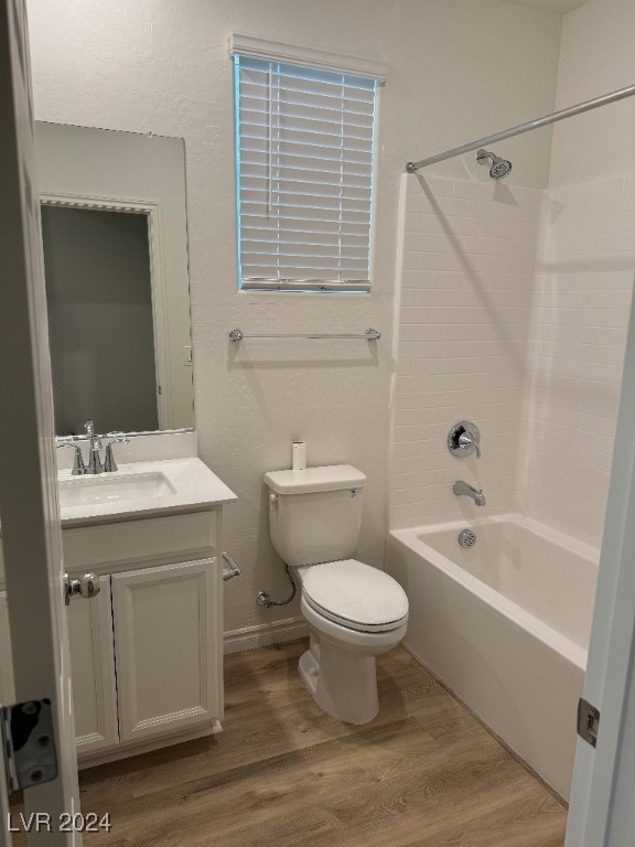 full bathroom featuring washtub / shower combination, hardwood / wood-style floors, toilet, and vanity