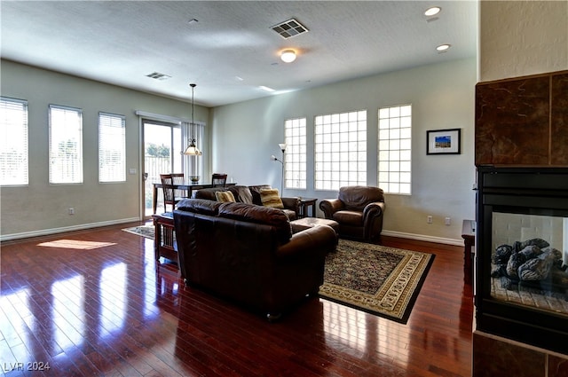 living room featuring a textured ceiling, dark hardwood / wood-style floors, and a multi sided fireplace