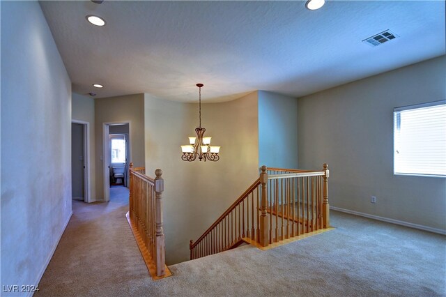 corridor with a chandelier, a textured ceiling, and carpet floors