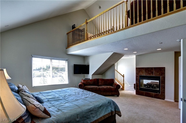 carpeted bedroom with high vaulted ceiling, a tiled fireplace, and a textured ceiling