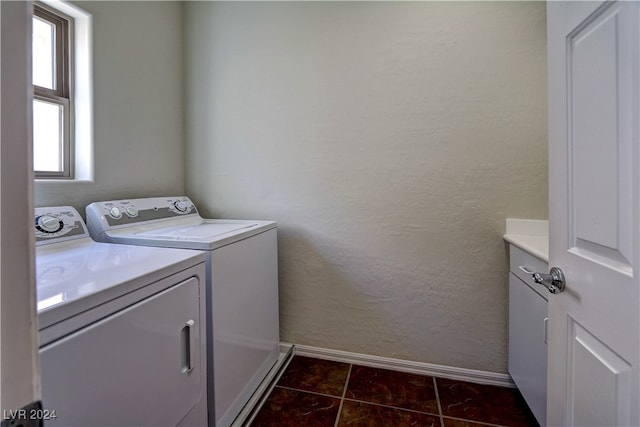 laundry room with dark tile patterned floors, a wealth of natural light, washing machine and clothes dryer, and cabinets