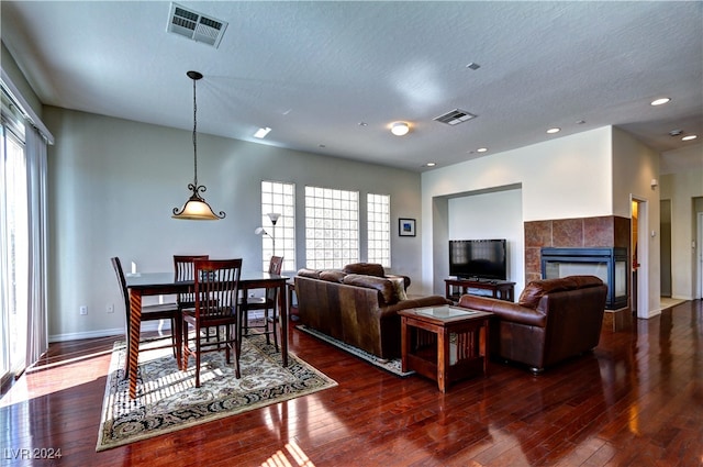 living room with a tiled fireplace, dark hardwood / wood-style floors, and a textured ceiling