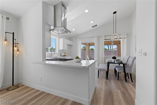 kitchen with white cabinets, light hardwood / wood-style floors, island exhaust hood, and a healthy amount of sunlight