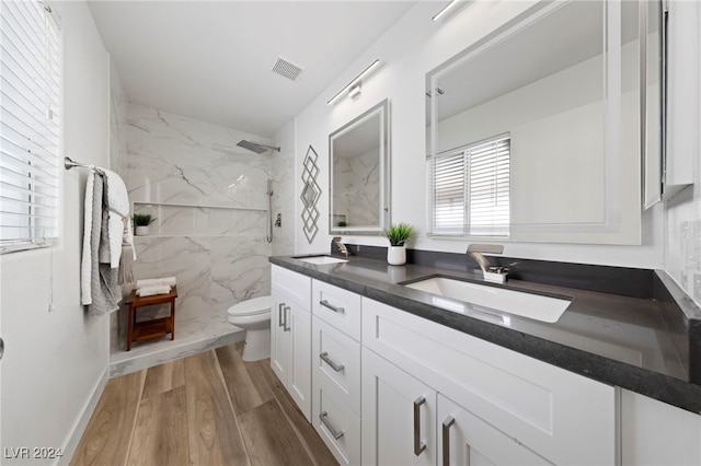 bathroom featuring tiled shower, toilet, hardwood / wood-style flooring, and vanity