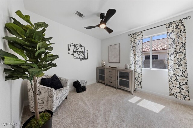 living area with ceiling fan and light carpet