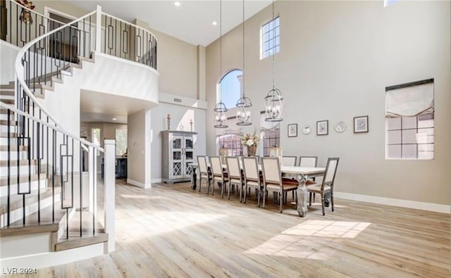 dining room with light hardwood / wood-style floors, a high ceiling, and a chandelier