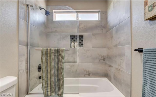 bathroom featuring toilet and tiled shower / bath