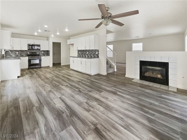 unfurnished living room with ceiling fan, a tiled fireplace, hardwood / wood-style floors, and sink