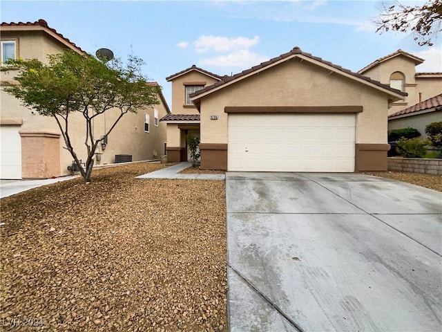 view of front facade with stucco siding, a garage, driveway, and a tiled roof