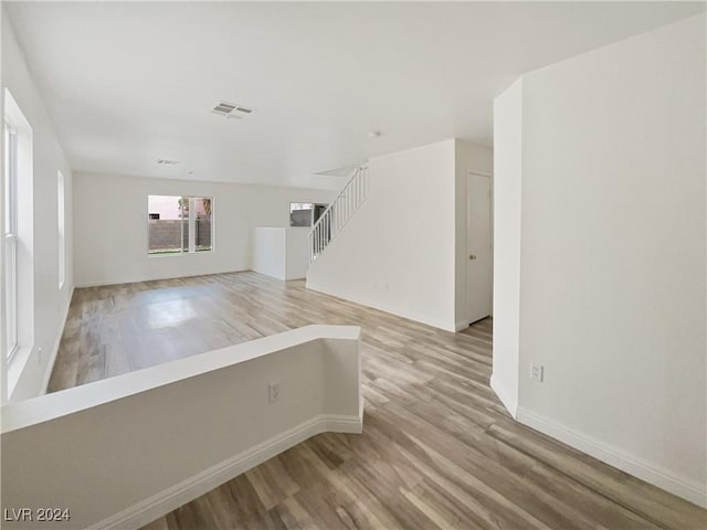 unfurnished room with stairs, light wood-style flooring, baseboards, and visible vents