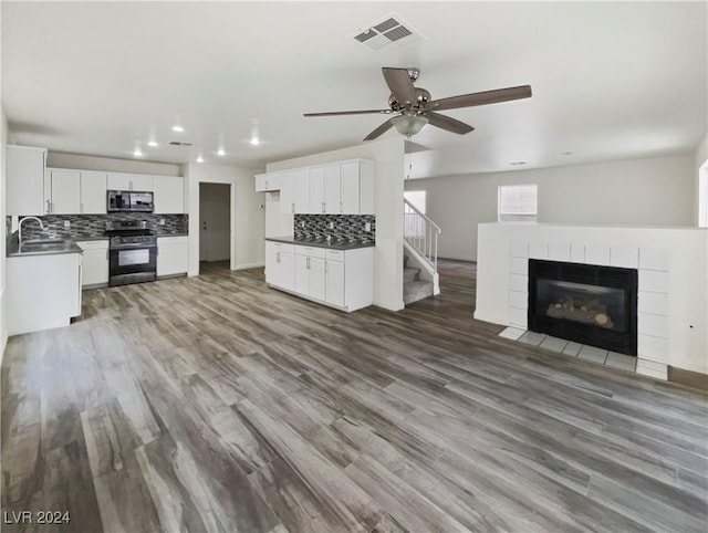 unfurnished living room with visible vents, a sink, wood finished floors, ceiling fan, and a tile fireplace