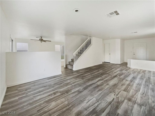 unfurnished living room featuring ceiling fan, visible vents, wood finished floors, and stairs