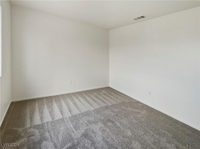 carpeted empty room featuring baseboards and visible vents