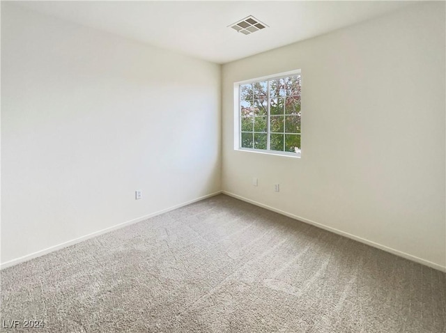 empty room with carpet flooring, baseboards, and visible vents