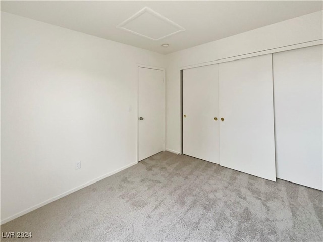 unfurnished bedroom with a closet, baseboards, attic access, and carpet flooring